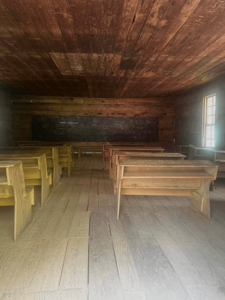 Inside a historic one-room schoolhouse with wooden pews